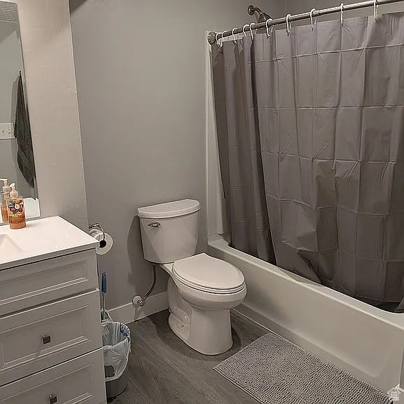 Bathroom with shower / bathtub combination with curtain, vanity, and wood finished floors