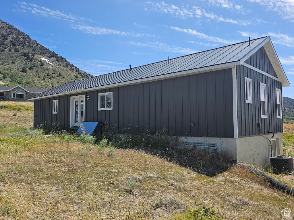 View of side of home with board and batten siding, a mountain view, and a metal roof