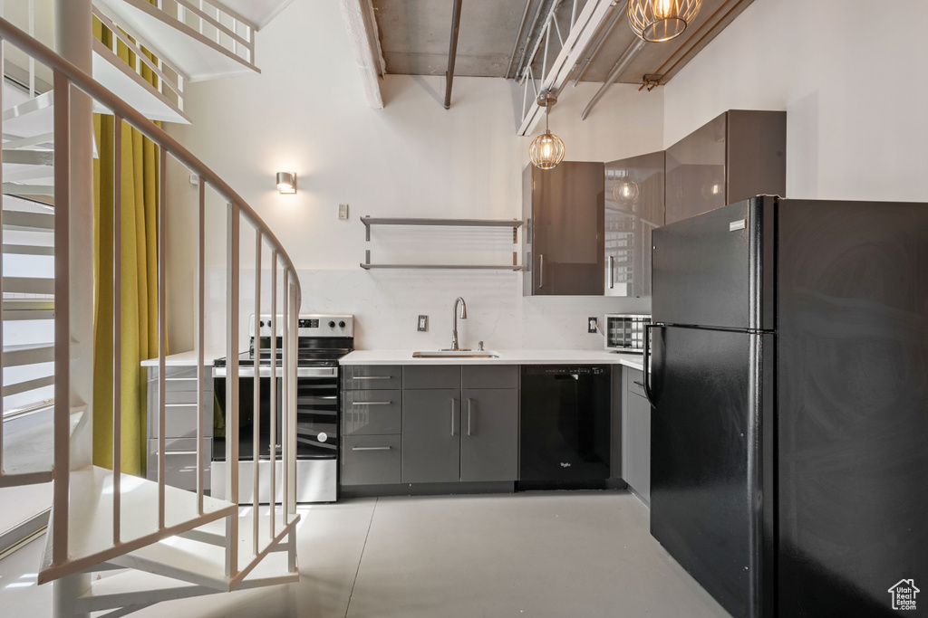 Kitchen with black appliances, gray cabinetry, finished concrete flooring, open shelves, and light countertops