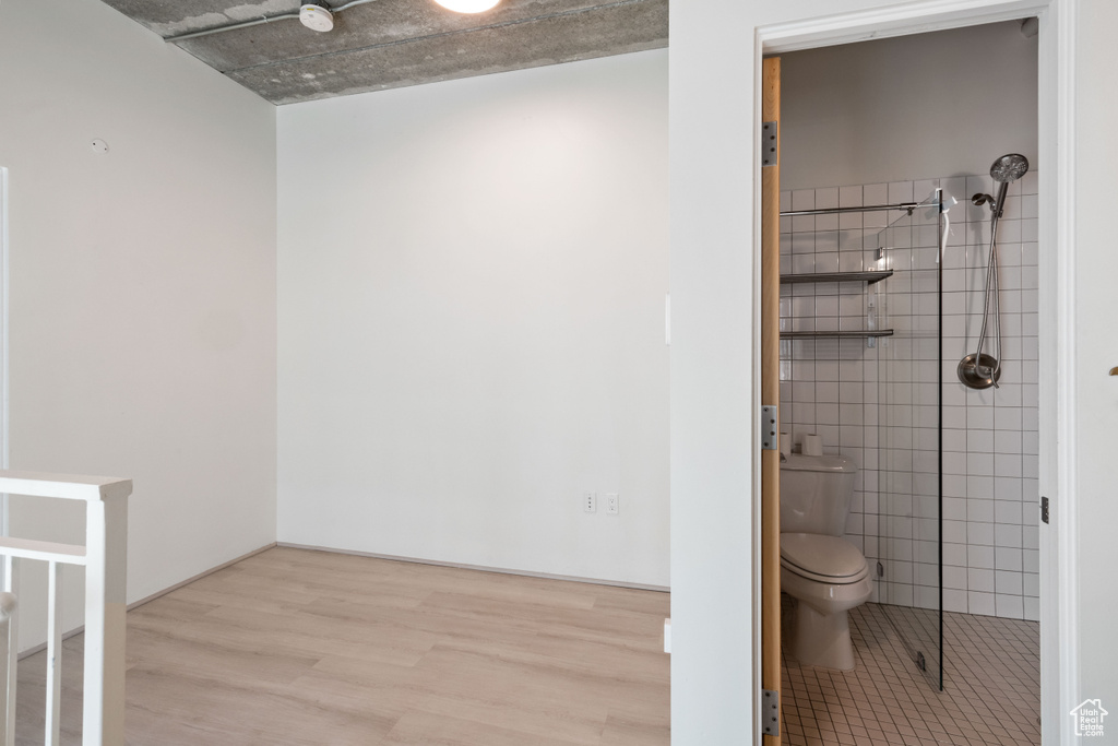 Bathroom with tile walls, wood finished floors, and tiled shower