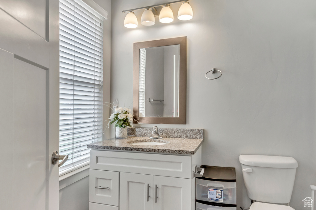 Bathroom with vanity, toilet, and plenty of natural light
