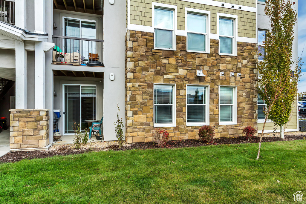 Property entrance with stone siding, a balcony, and a yard