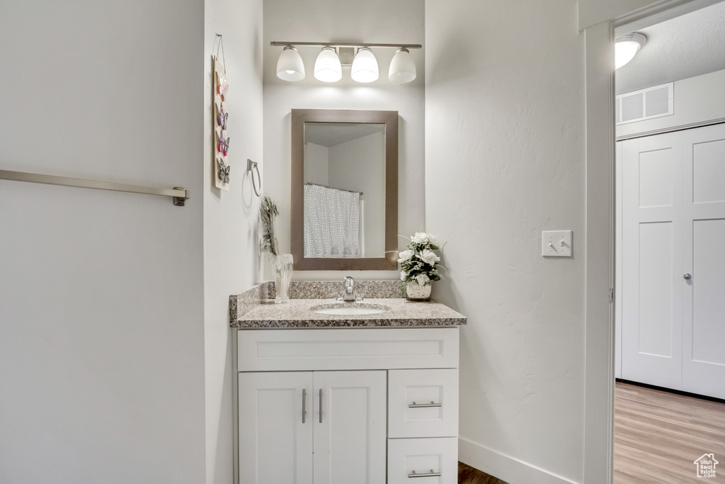 Bathroom featuring vanity, wood finished floors, and baseboards