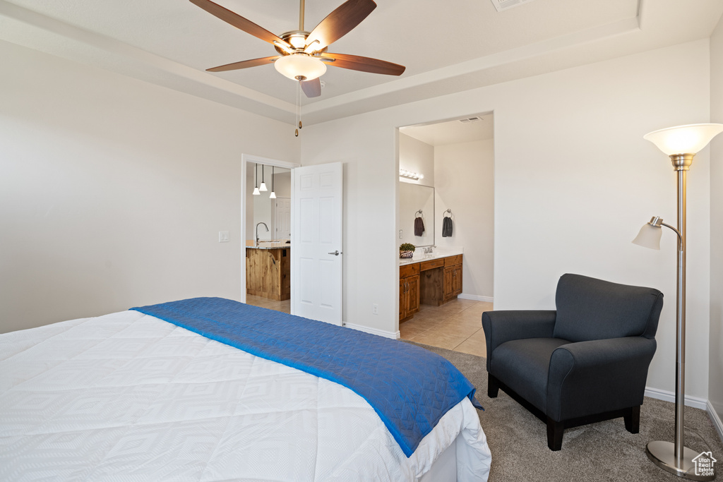 Bedroom featuring a tray ceiling, ensuite bath, a ceiling fan, and light tile patterned floors