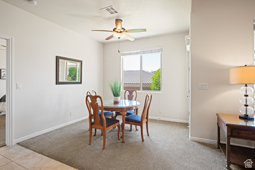 Dining space featuring ceiling fan and light carpet