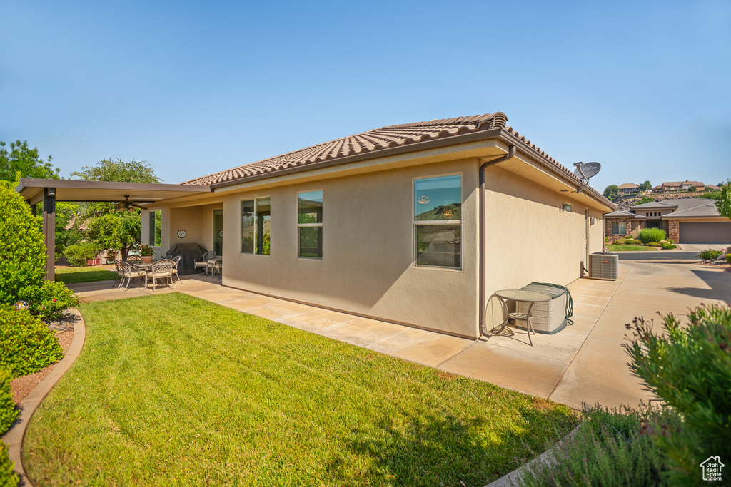 Rear view of property featuring a yard, a ceiling fan, a patio area, a tiled roof, and stucco siding