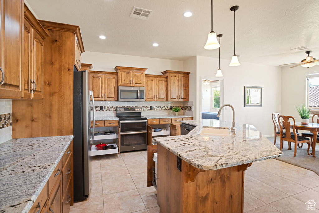 Kitchen featuring appliances with stainless steel finishes, a ceiling fan, a kitchen bar, backsplash, and recessed lighting