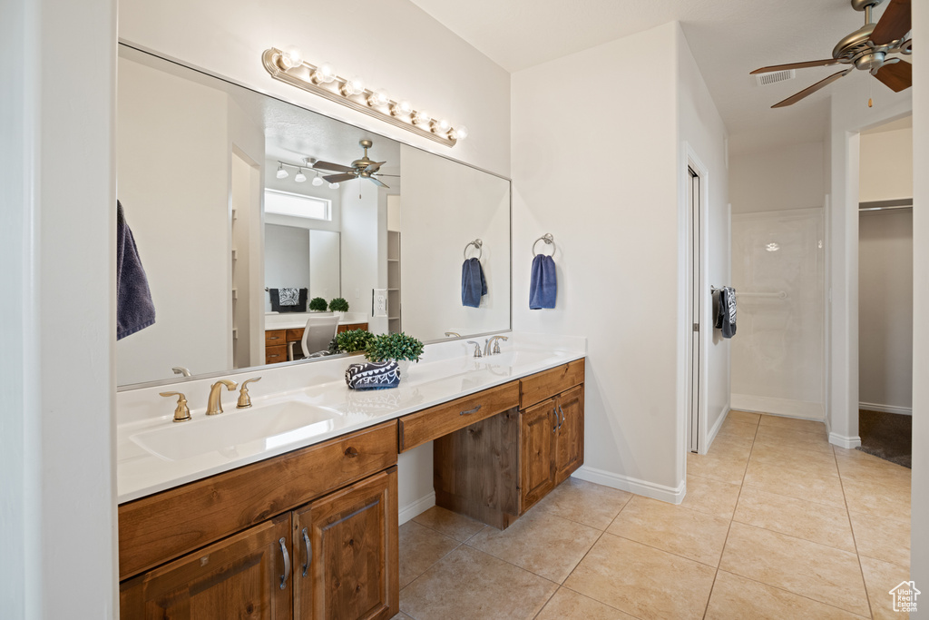 Bathroom featuring a ceiling fan, double vanity, tile patterned floors, and a spacious closet