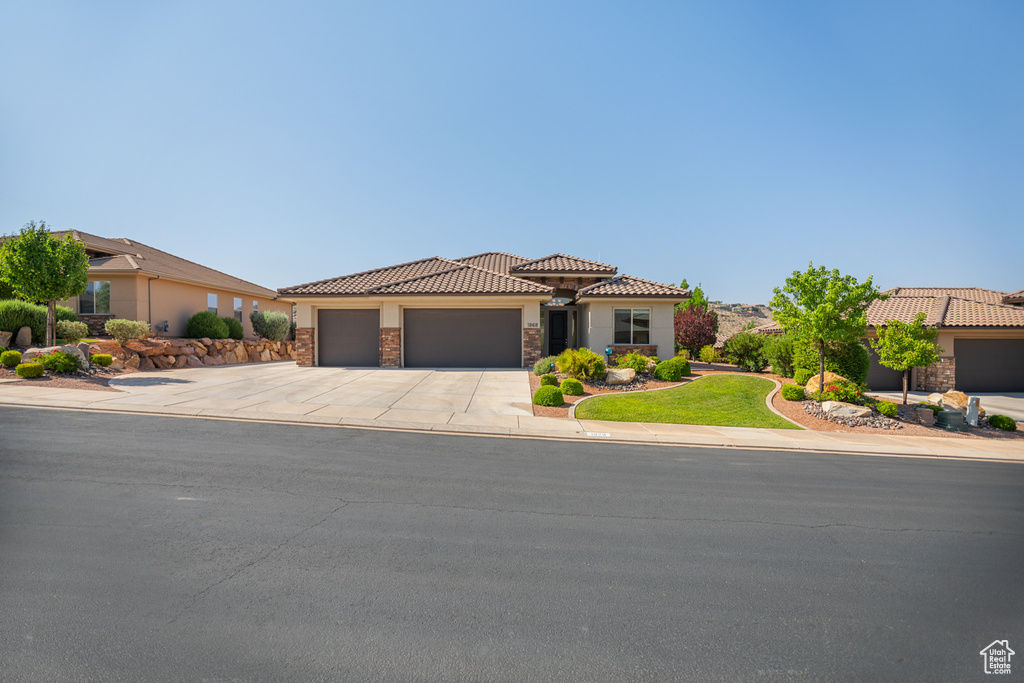 Mediterranean / spanish-style home with stone siding, a garage, concrete driveway, stucco siding, and a tiled roof