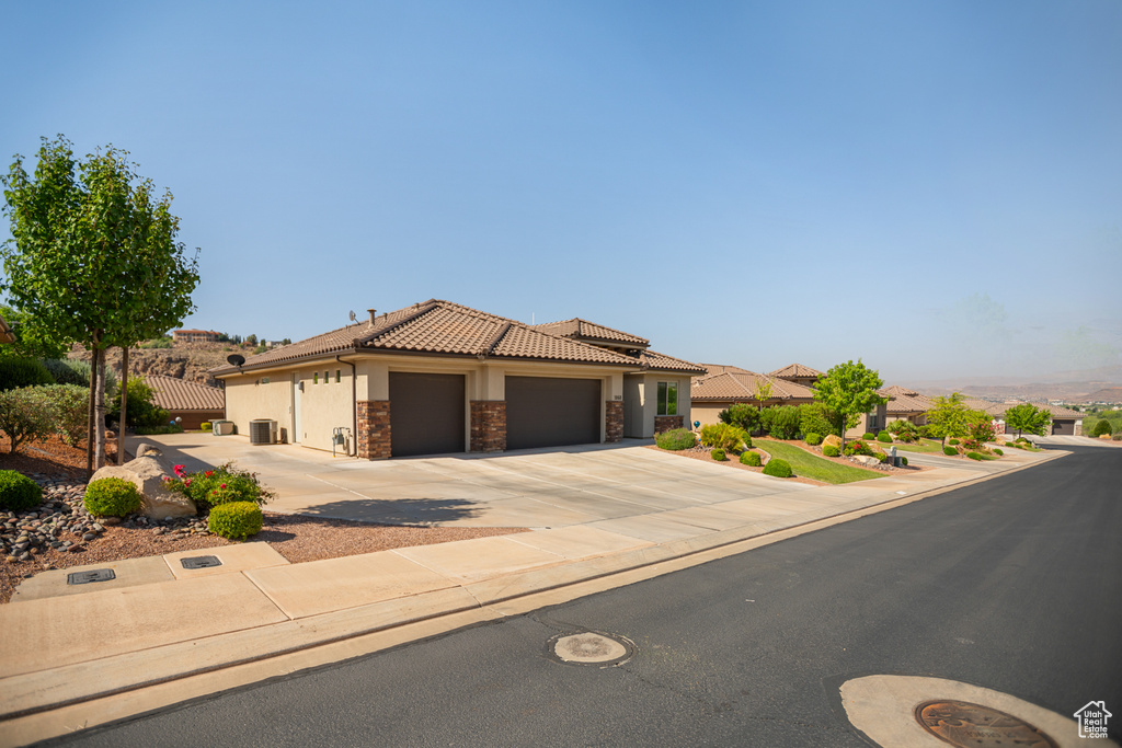 Mediterranean / spanish-style home with stone siding, stucco siding, an attached garage, driveway, and a tile roof