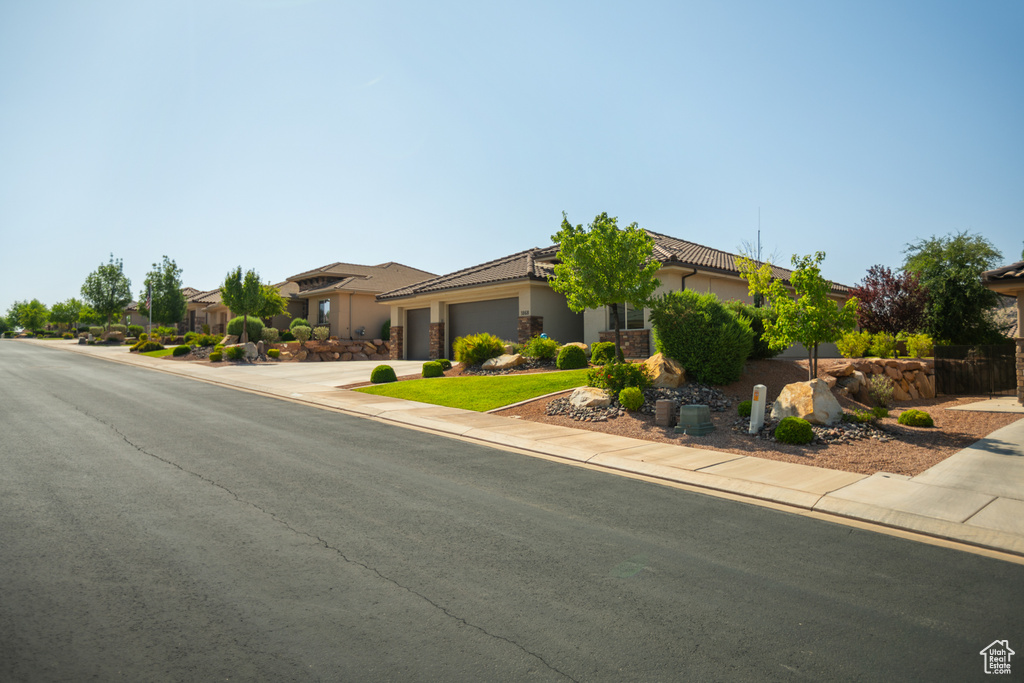 View of front facade featuring a garage, driveway, stucco siding, and a tiled roof