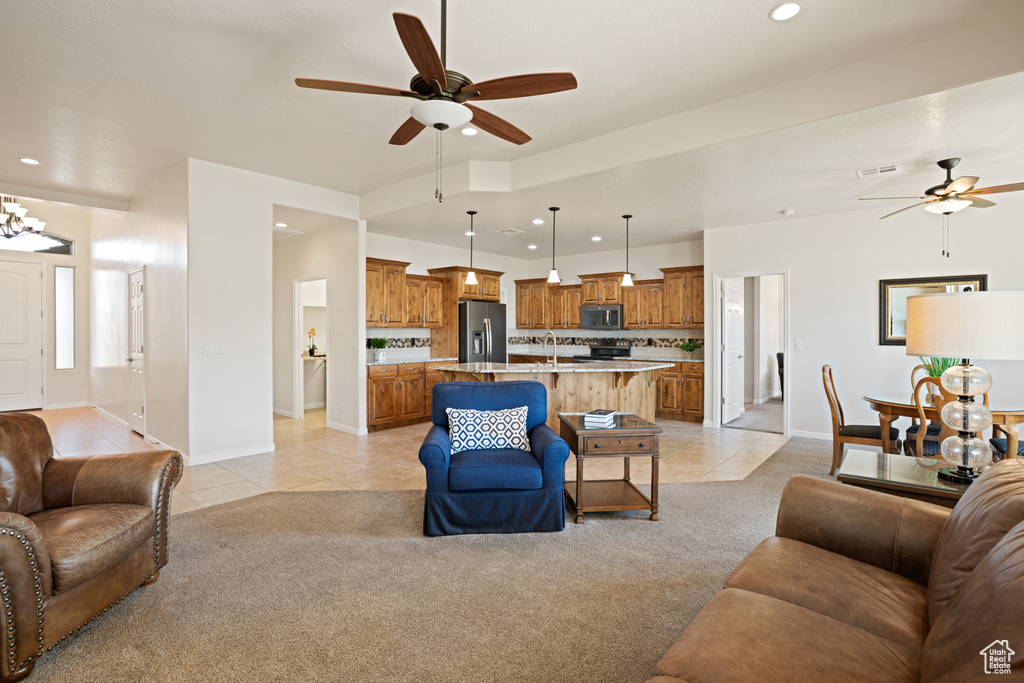 Living area with ceiling fan, light tile patterned floors, recessed lighting, light carpet, and a chandelier