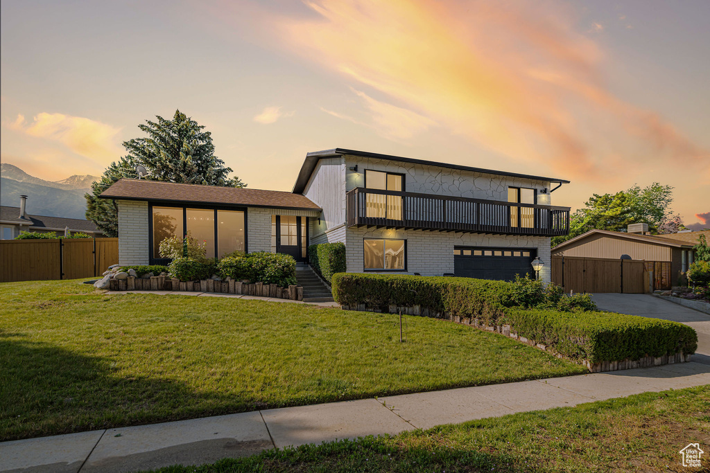 View of front of property featuring a balcony, brick siding, a garage, concrete driveway, and a mountain view