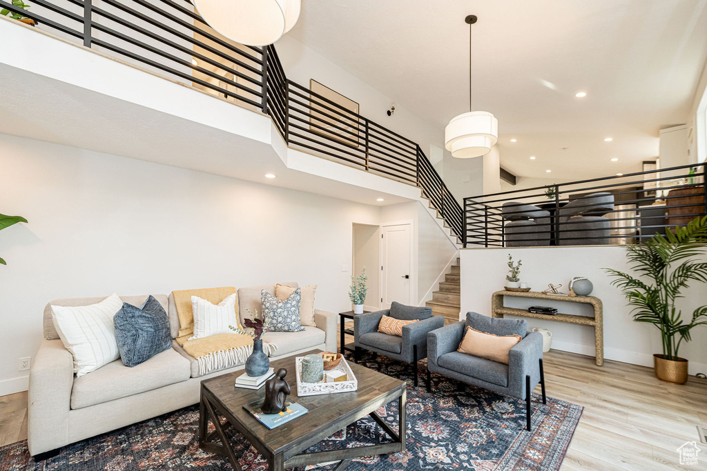 Living room featuring a high ceiling, wood finished floors, recessed lighting, and stairway