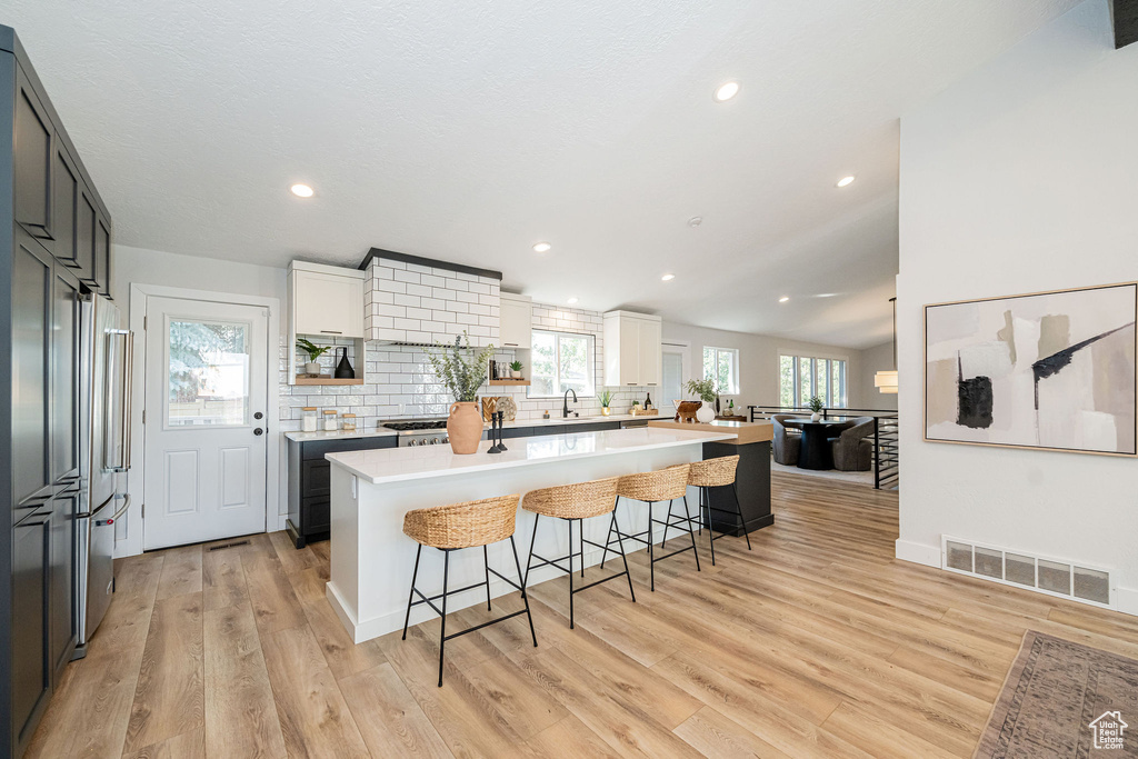 Kitchen with a kitchen bar, high end refrigerator, tasteful backsplash, light countertops, and a kitchen island
