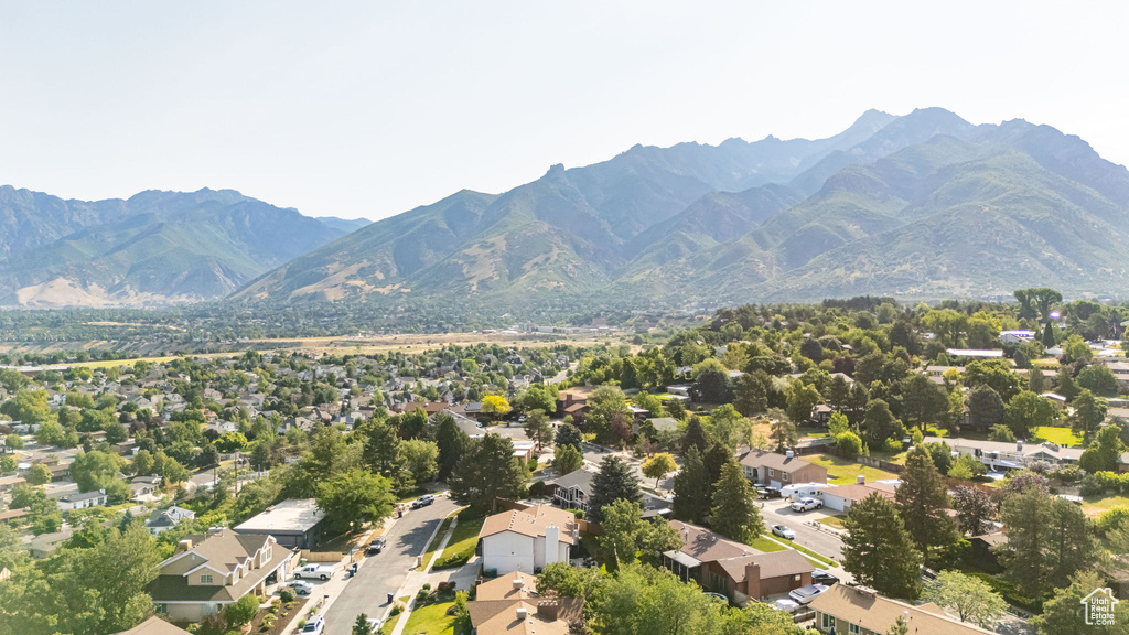 Aerial view of property and surrounding area featuring a mountain backdrop and nearby suburban area
