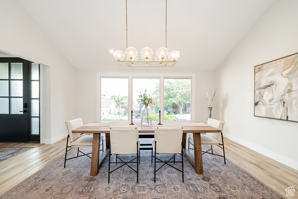 Dining area featuring vaulted ceiling, a chandelier, and light wood-style flooring