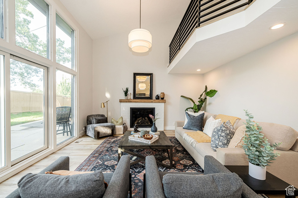Living area with a high ceiling, wood finished floors, a brick fireplace, and recessed lighting