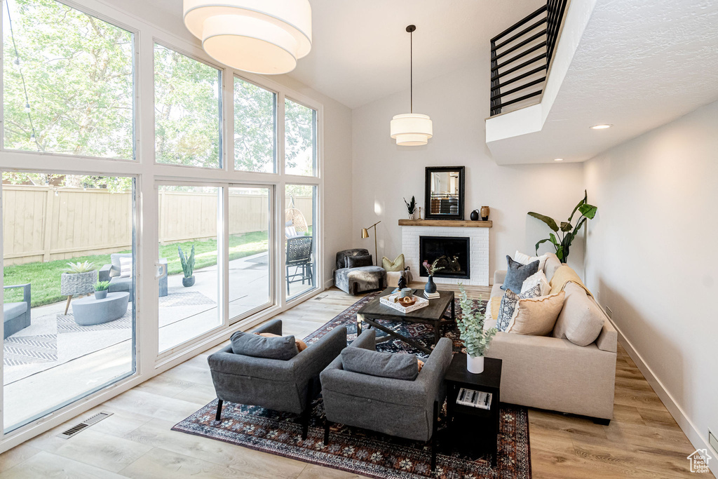 Living area featuring a towering ceiling, a fireplace, and wood finished floors