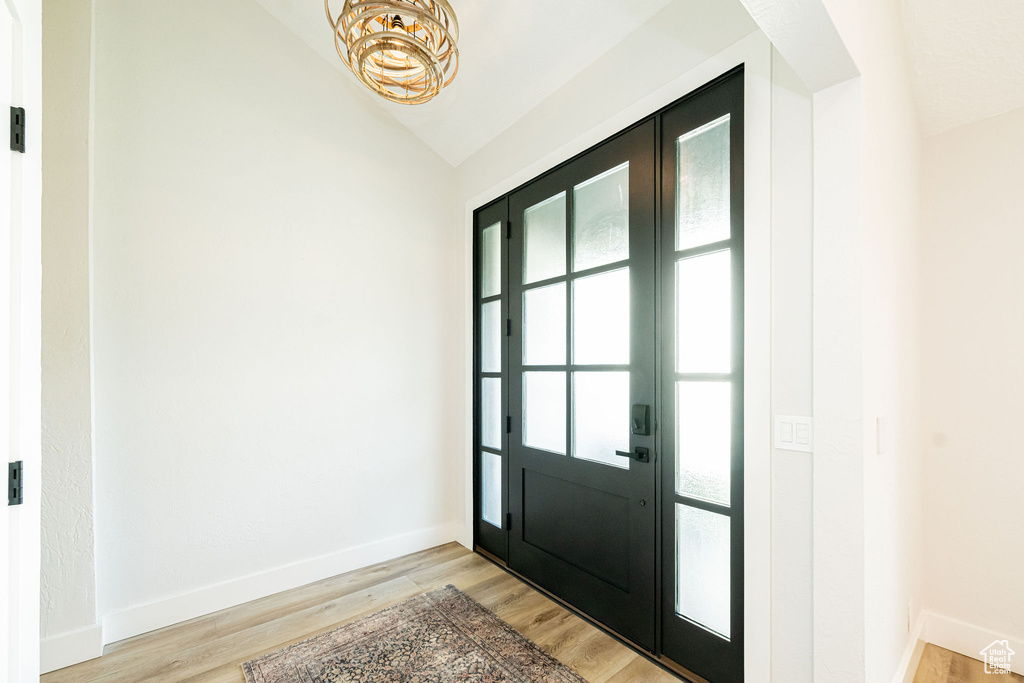 Entrance foyer with vaulted ceiling, a chandelier, and light wood-type flooring