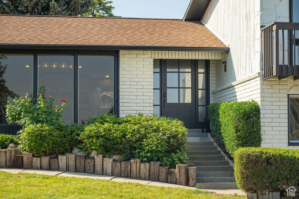Property entrance featuring brick siding, roof with shingles, and board and batten siding