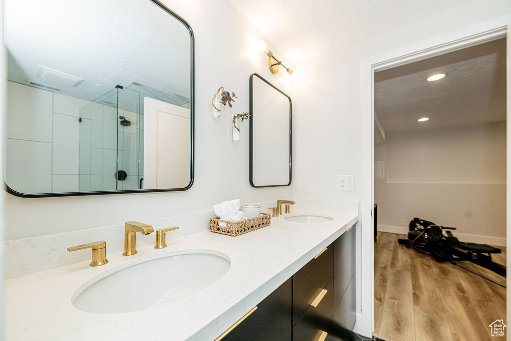 Full bath with a stall shower, double vanity, wood finished floors, and recessed lighting