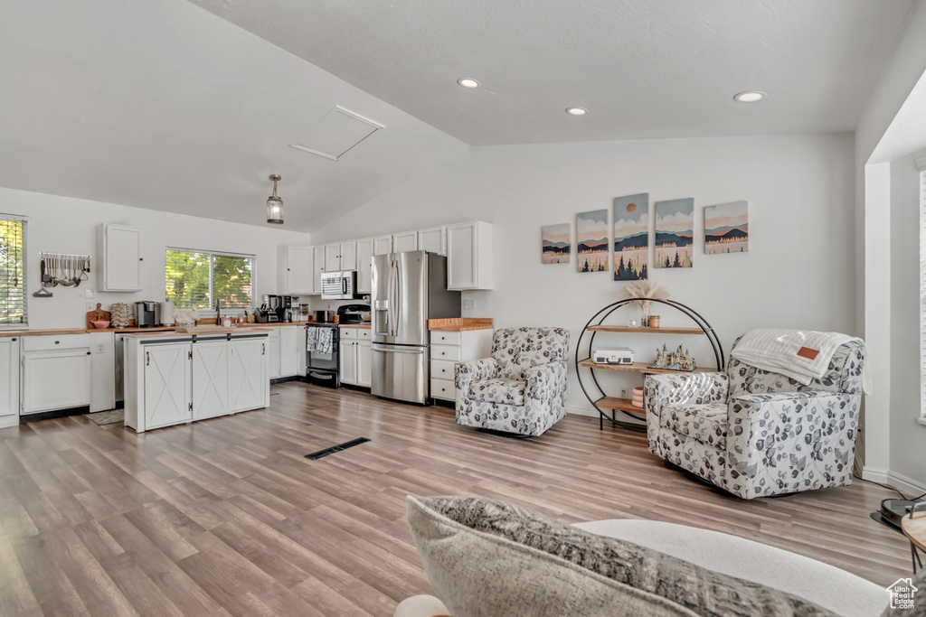 Living area featuring lofted ceiling, light wood-style flooring, attic access, and recessed lighting