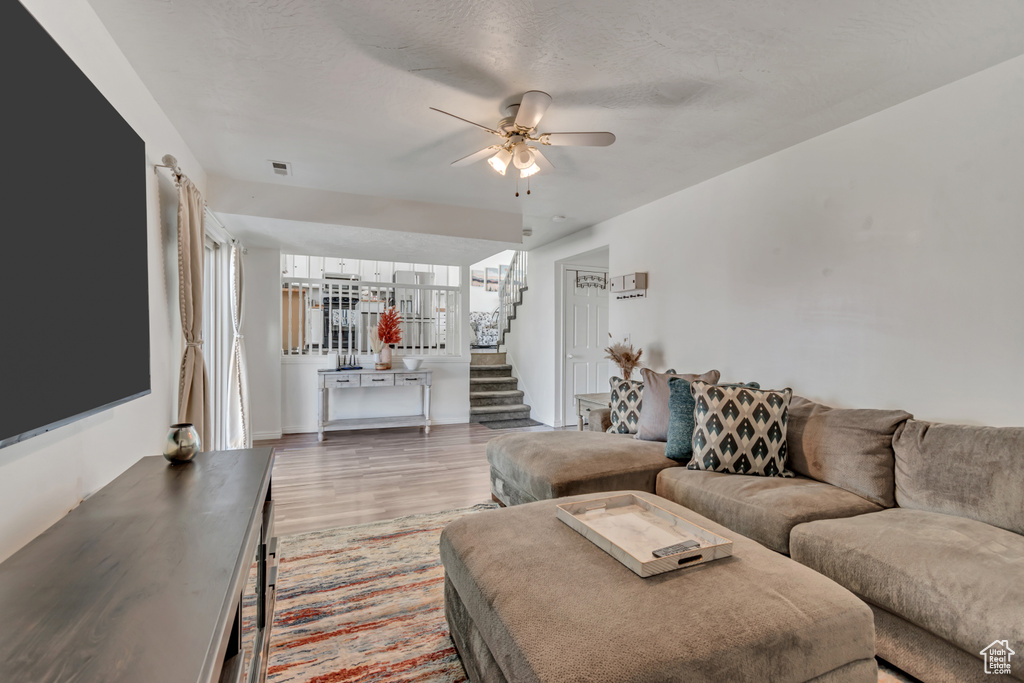 Living room featuring wood finished floors, stairway, and a ceiling fan