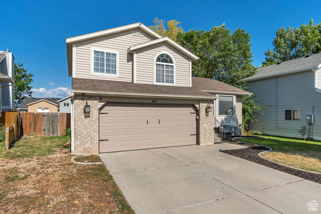 View of front of house featuring brick siding, an attached garage, driveway, and a shingled roof