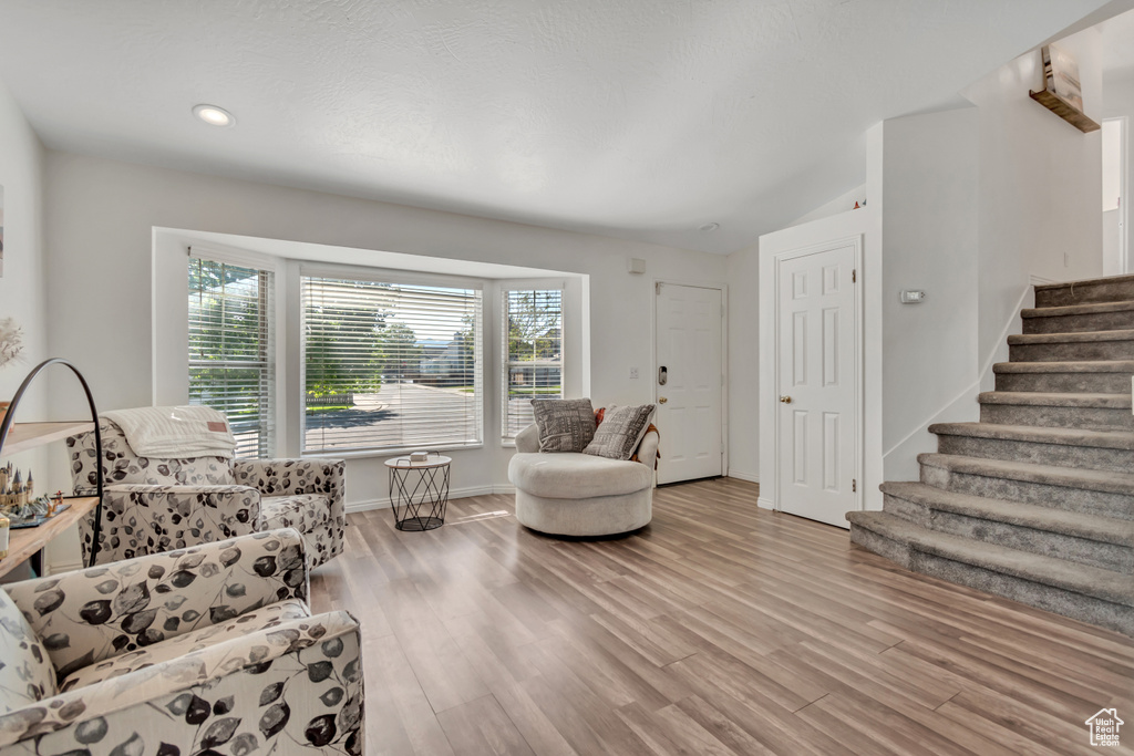 Living area featuring stairs, light wood-style floors, recessed lighting, and lofted ceiling