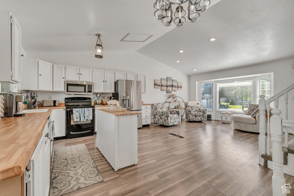 Kitchen featuring appliances with stainless steel finishes, wooden counters, lofted ceiling, white cabinets, and a center island