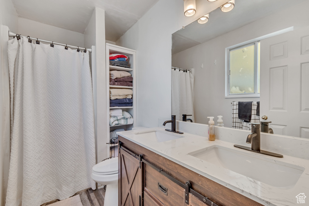 Bathroom with double vanity, wood finished floors, and a shower with curtain
