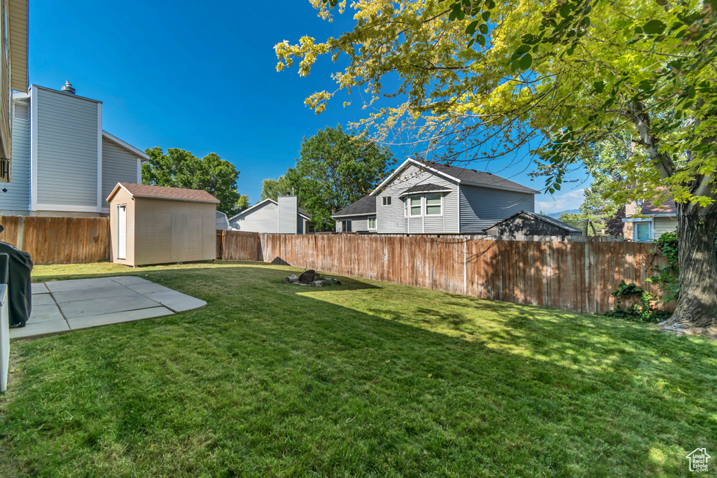 Fenced backyard featuring a patio and a storage shed