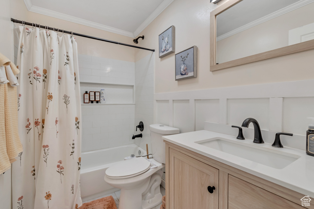 Bathroom featuring vanity, crown molding, shower / bath combination with curtain, and a wainscoted wall