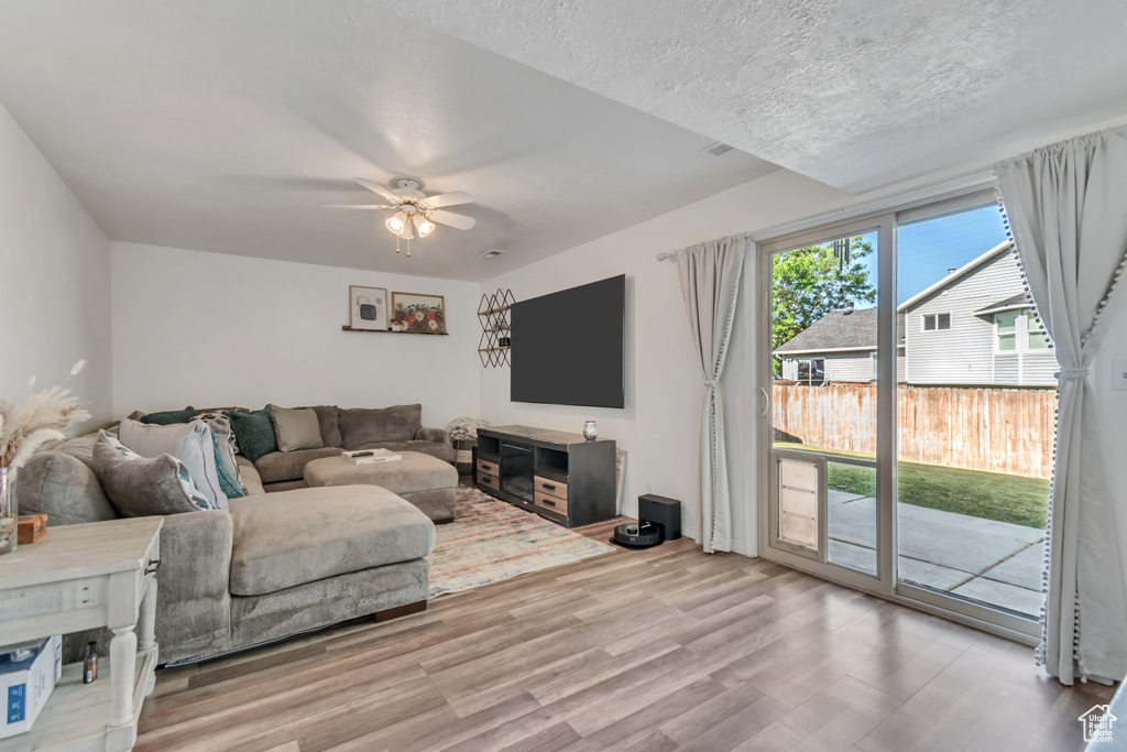 Living area with wood finished floors, a ceiling fan, and a textured ceiling