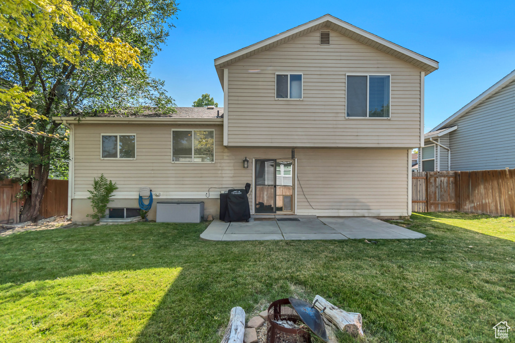 Rear view of house with a fenced backyard and a patio area