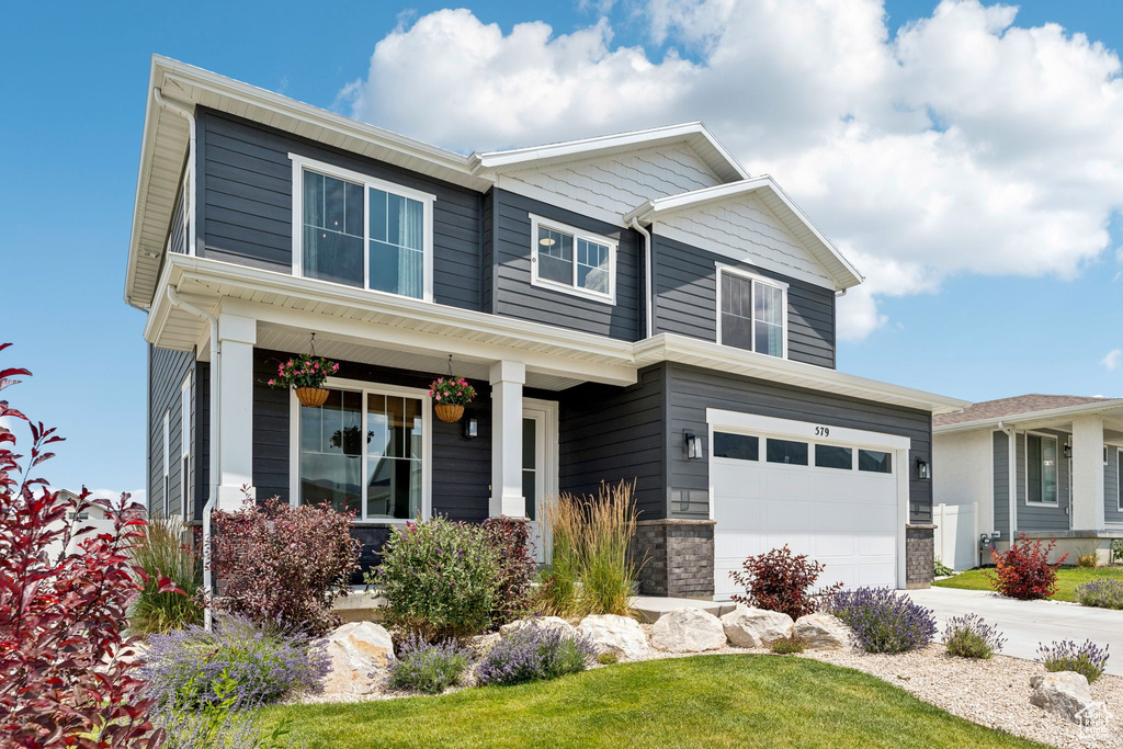 Craftsman inspired home with an attached garage, concrete driveway, and a porch