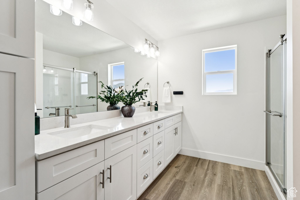 Full bathroom featuring double vanity, a shower stall, and wood finished floors