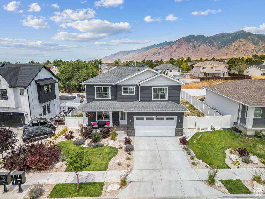 View of front facade featuring driveway, a garage, a mountain view, a residential view, and a shingled roof