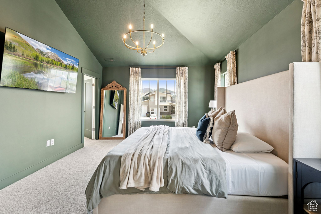 Bedroom featuring a chandelier, vaulted ceiling, and carpet floors