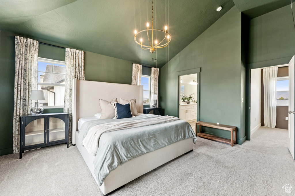 Carpeted bedroom featuring a chandelier, multiple windows, ensuite bathroom, and high vaulted ceiling