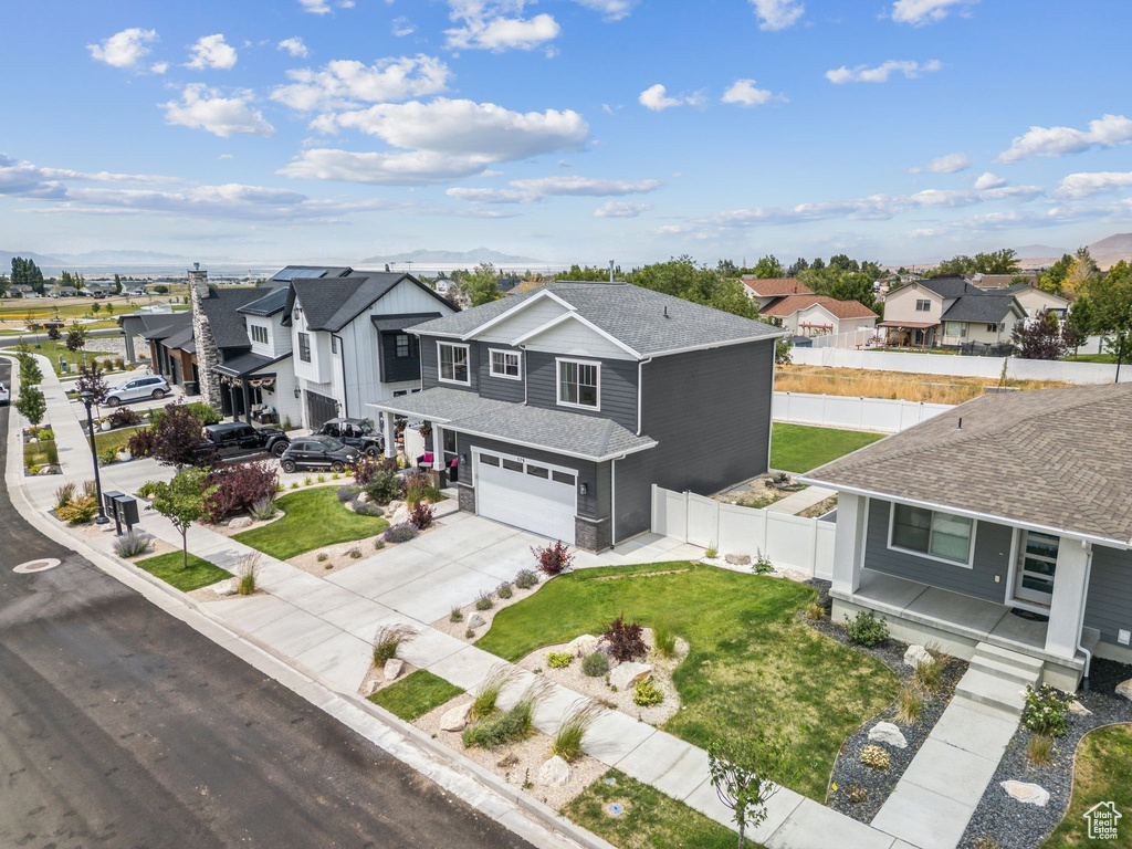 View of front facade featuring a residential view, a garage, concrete driveway, and roof with shingles