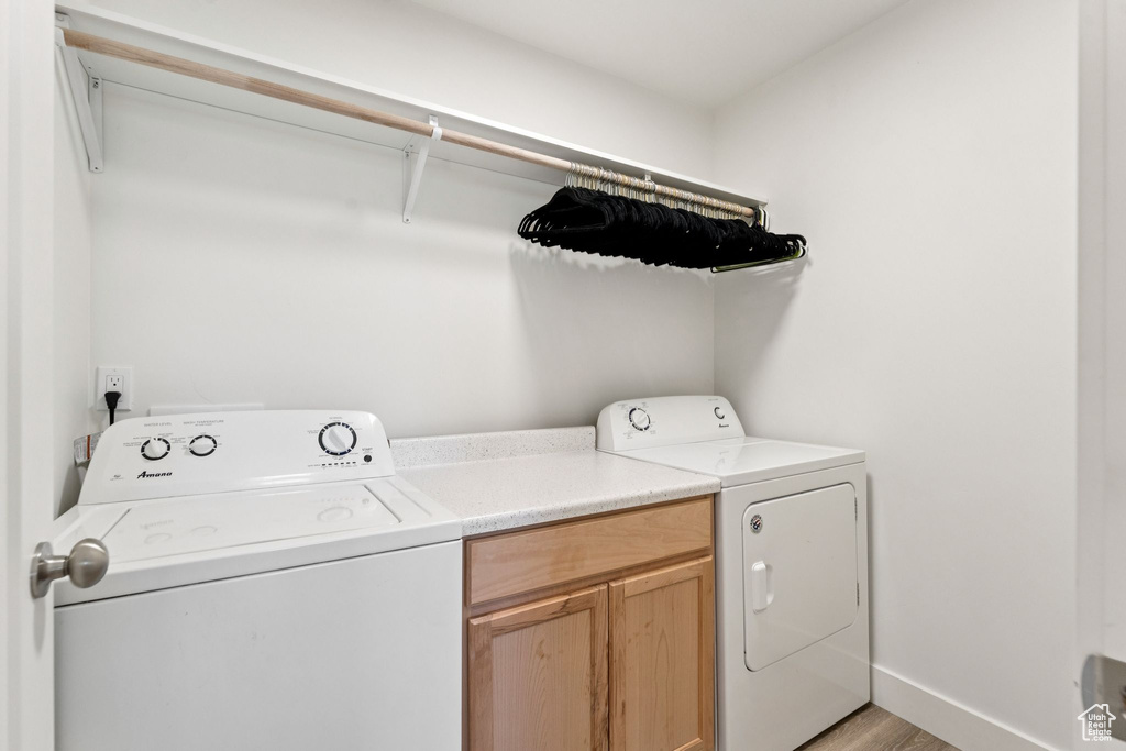 Laundry area featuring washing machine and dryer, light wood finished floors, and cabinet space