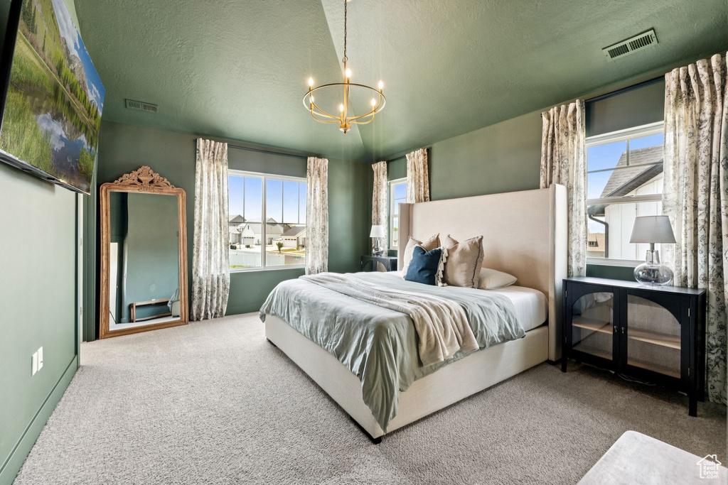 Bedroom with a chandelier, carpet flooring, multiple windows, and a textured ceiling