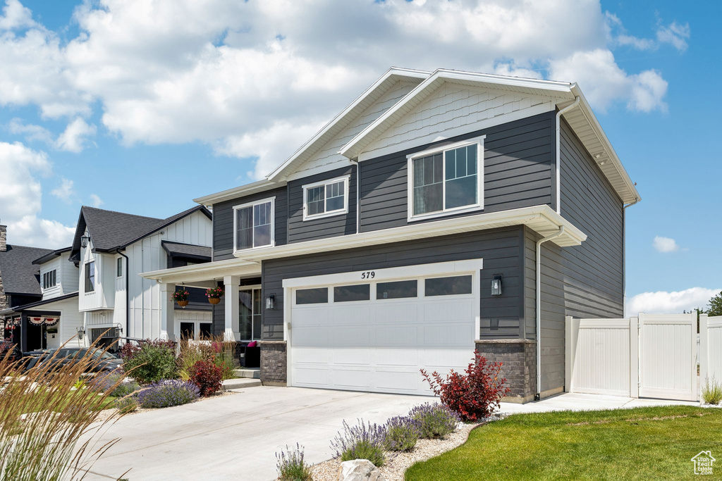 View of front of property featuring a garage, concrete driveway, stone siding, and board and batten siding