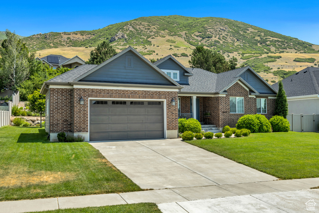 View of front of property featuring a garage, concrete driveway, brick siding, and a mountain view