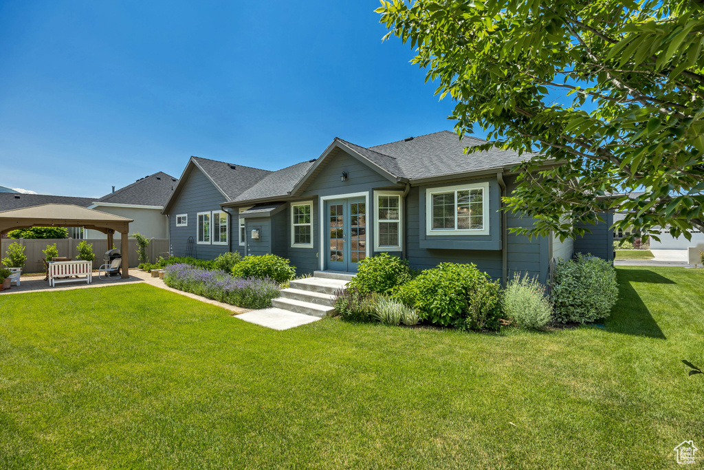 View of front of house with a gazebo, french doors, a patio, and roof with shingles