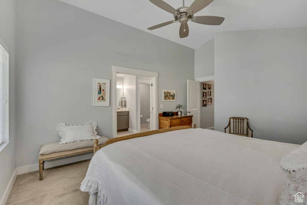 Bedroom with high vaulted ceiling, multiple windows, light carpet, ensuite bath, and ceiling fan