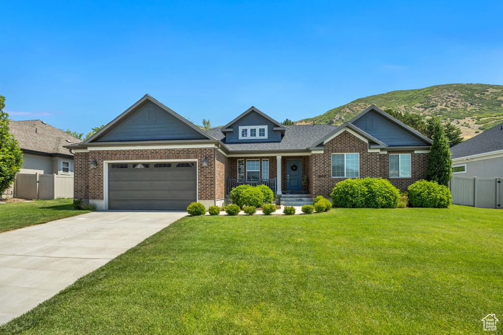 View of front of property featuring brick siding, concrete driveway, a garage, a mountain view, and roof with shingles