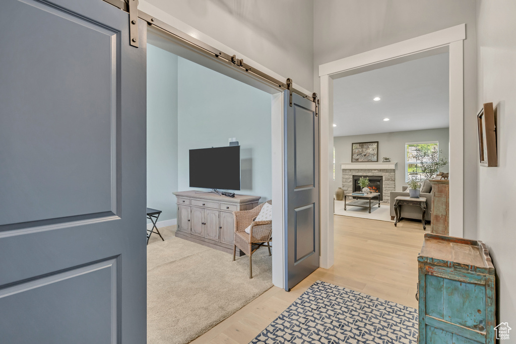 Hall with a barn door, light wood-style flooring, and recessed lighting